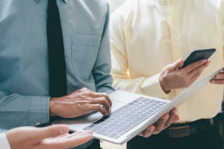 Mann mit Handy und Laptop in der Hand, symbolisiert digitale Vernetzung, Kommunikation und moderne Arbeitsweise – Werte, die Medoplan bei der Praxisnachfolge und -beratung unterstützt.