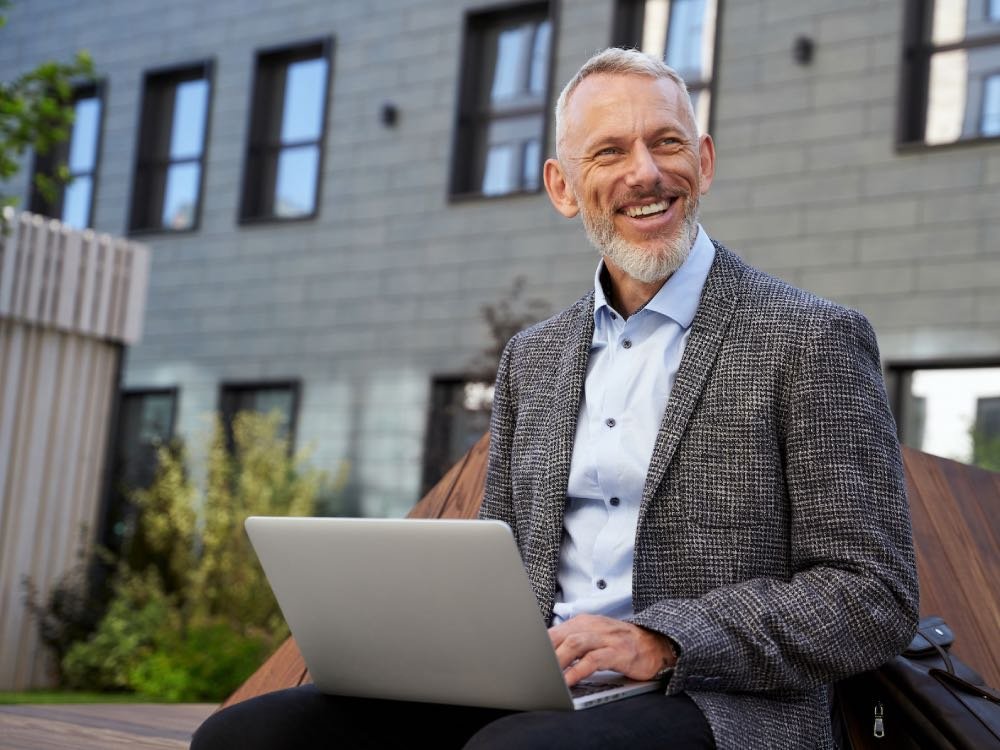 Älterer Mann mit Laptop, symbolisiert Erfahrung, digitale Kompetenz und die Anpassung an neue Technologien – Werte, die Medoplan in der Praxisnachfolge unterstützt.