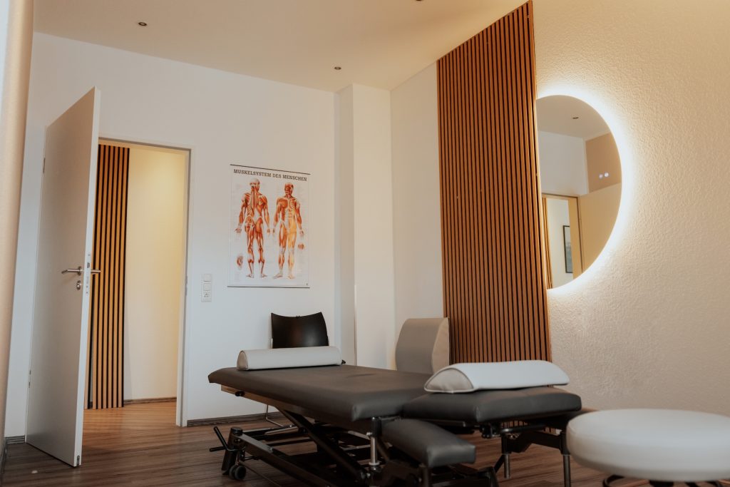 Behandlungsraum einer Therapieeinrichtung mit Liege und Anatomieposter