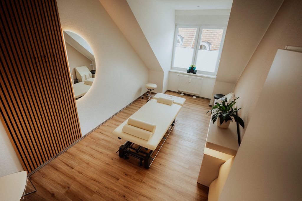 Behandlungsraum mit Liege und Holzlamellenwand