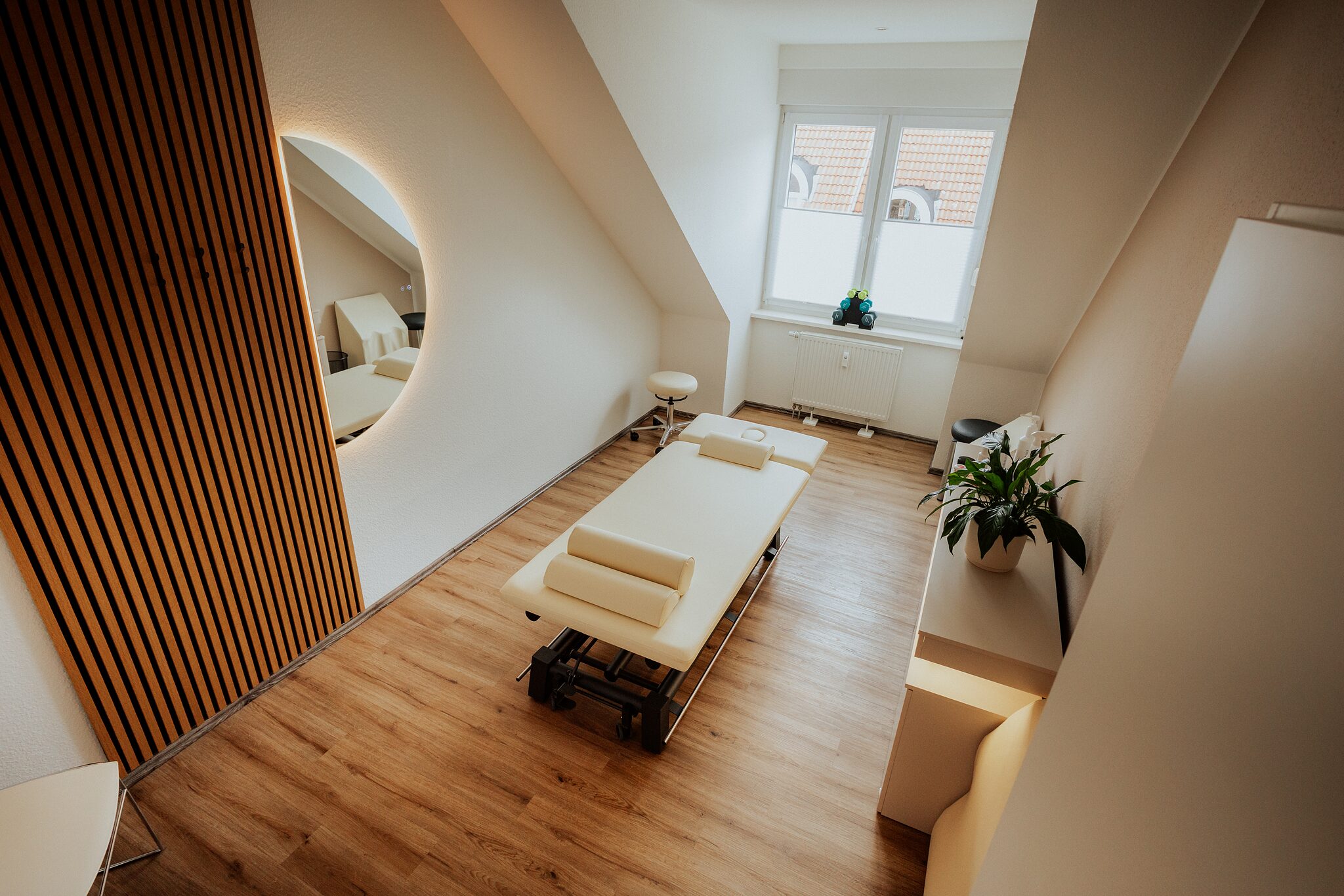 Behandlungsraum einer Physiotherapiepraxis mit Behandlungsliege und Holzlamellenwand